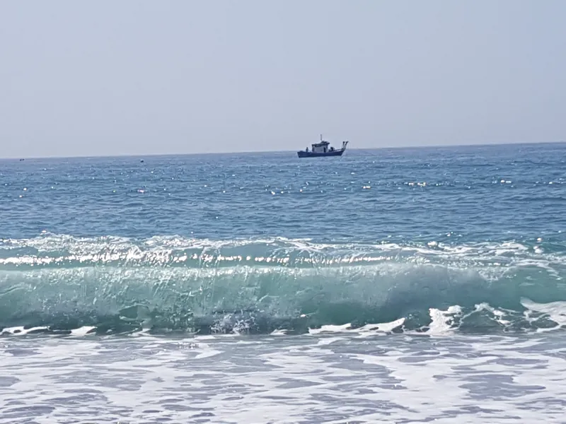 Ola turquesa a punto de romper con un barco pequeño en el horizonte