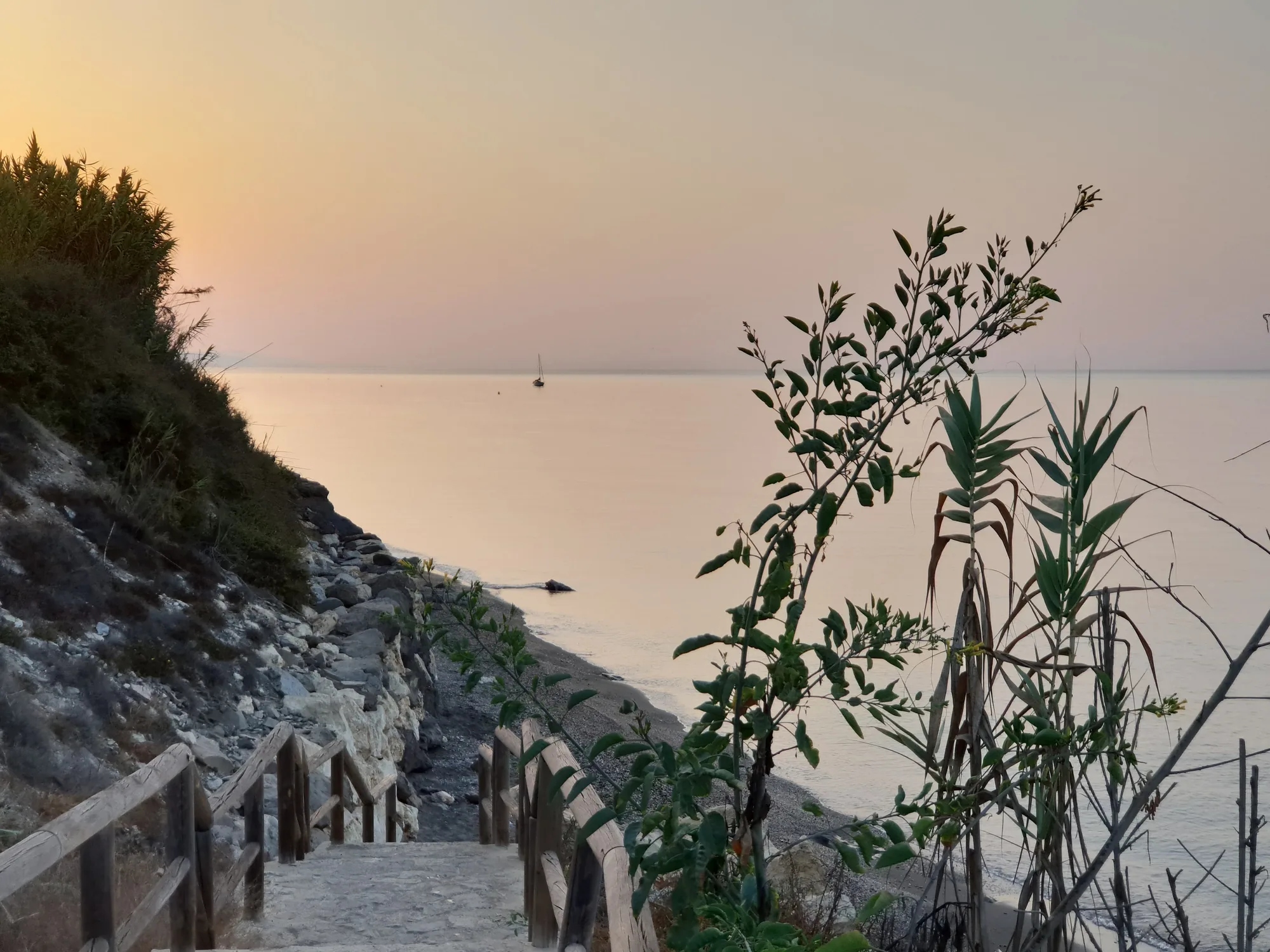 Escaleras de madera que bajan por un acantilado hacia el mar al amanecer en Valle-Niza