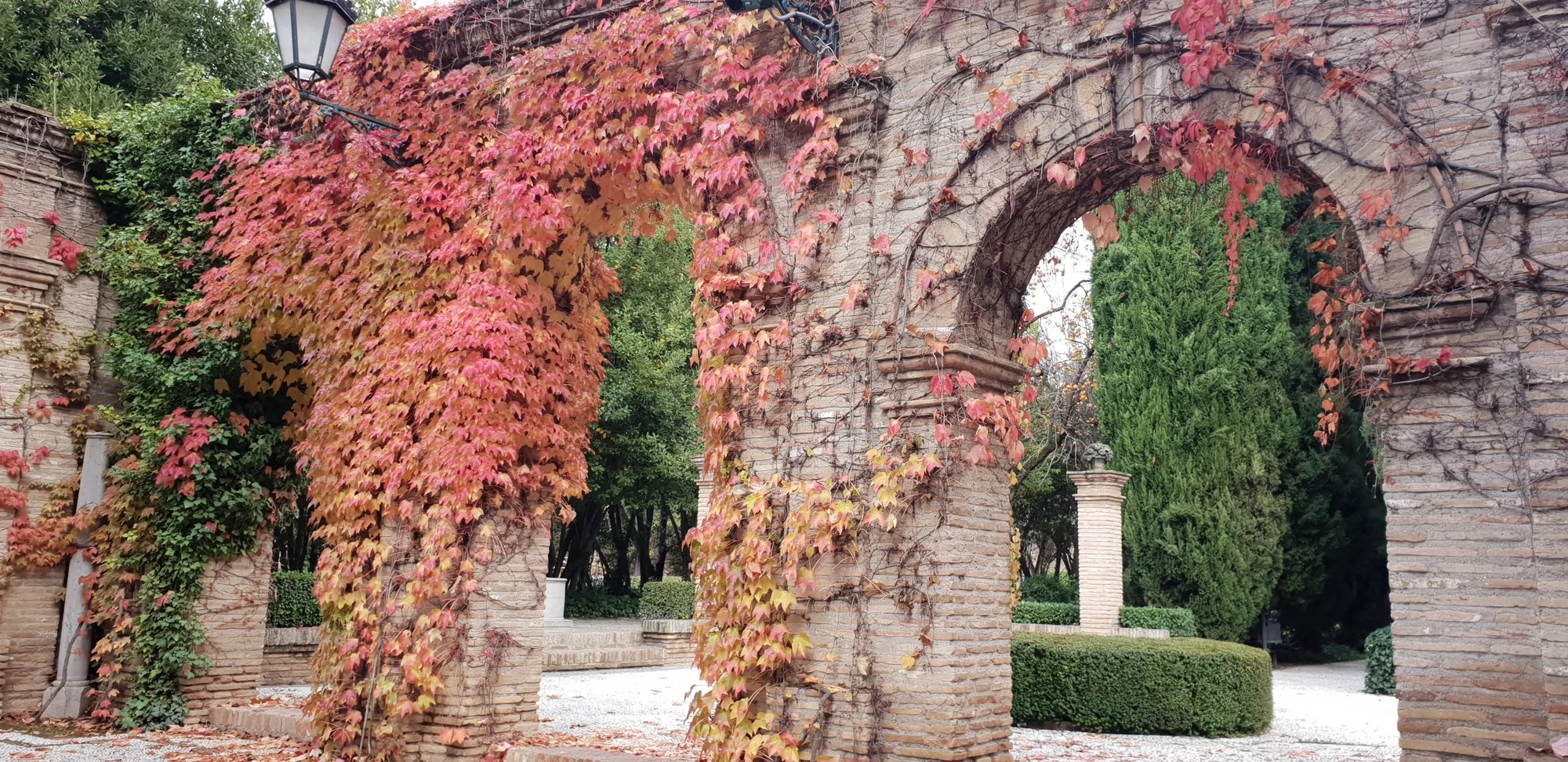Arcos de ladrillo cubiertos de hiedra roja en un jardín en Granada