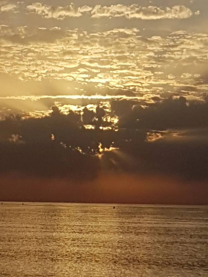 Nubes doradas con rayos de sol sobre un mar brillante en Valle-Niza