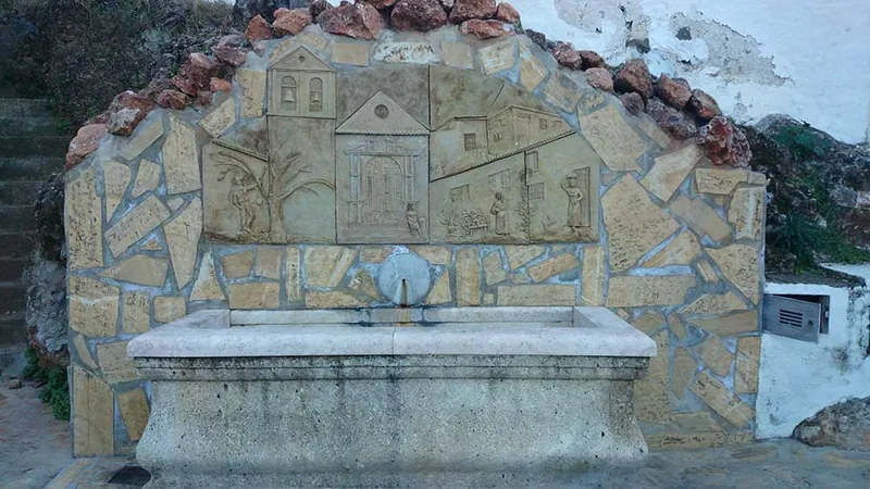 Fuente de piedra con un relieve de casas del pueblo