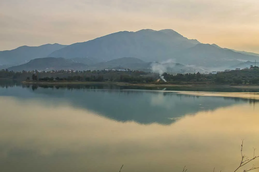 Montaña reflejada en las aguas tranquilas de un embalse al amanecer en La Viñuela