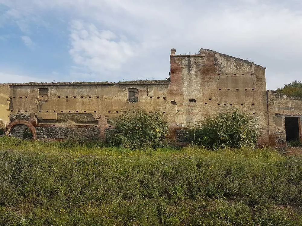 Edificio antiguo de ladrillo en ruinas rodeado de hierba en Vélez-Málaga