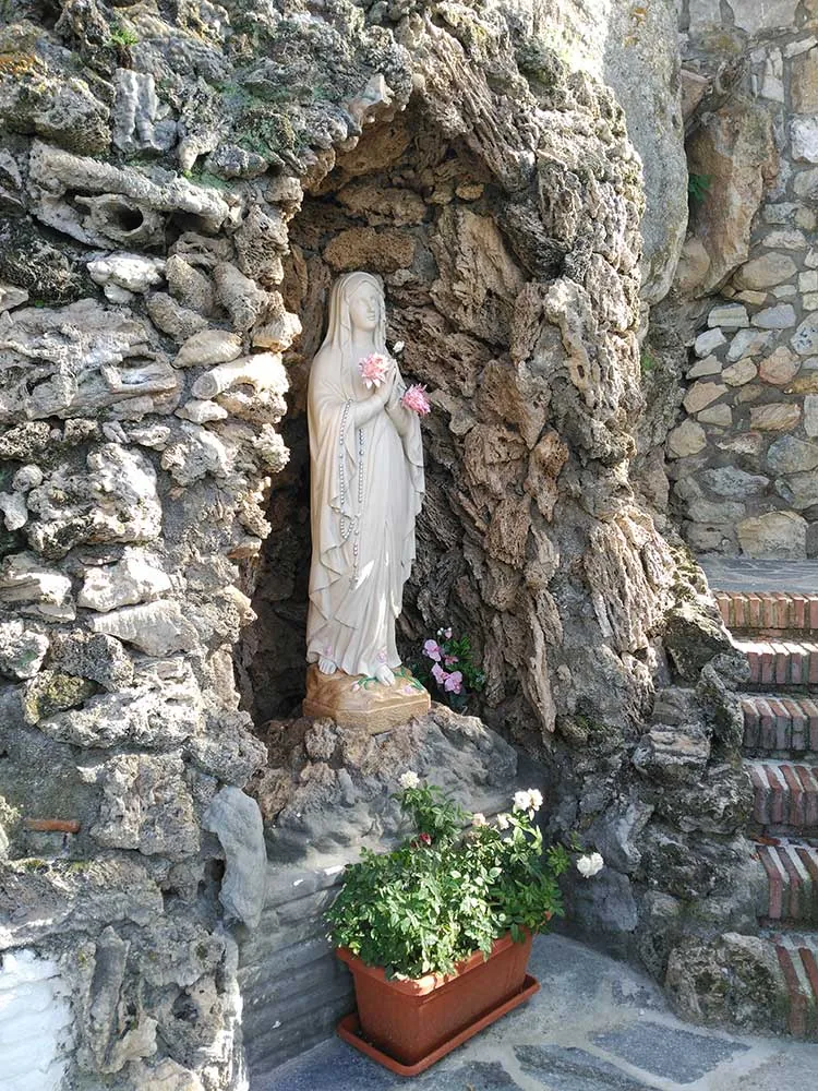 Imagen de la Virgen en una hornacina de piedra con flores en Canillas de Aceituno